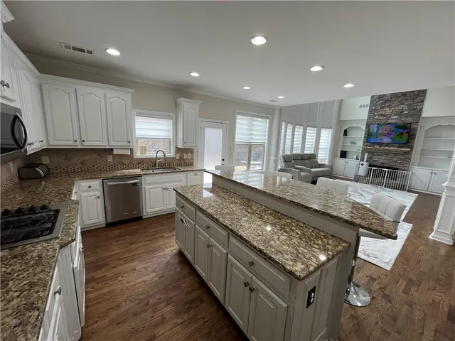 a large kitchen with stainless steel appliances granite countertop a stove a sink and a granite counter tops