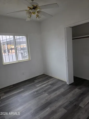 an empty room with wooden floor fan and windows