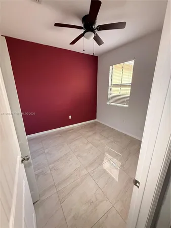 an empty room with a chandelier fan and windows