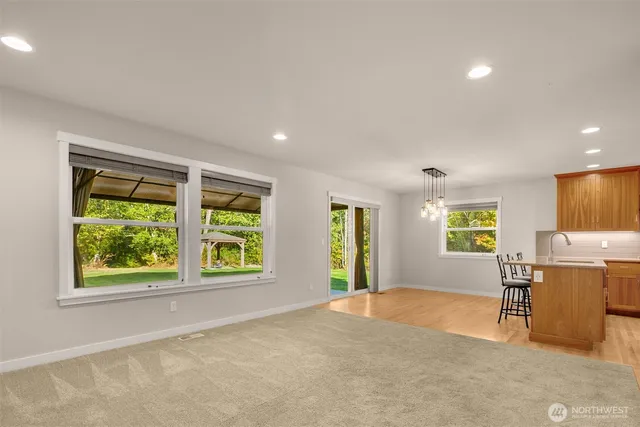 a view of an empty room with window and a kitchen