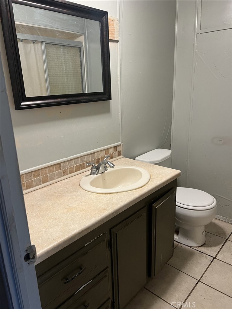 31596 Allen Avenue Homeland, CA 92548 - Photo 19 of 22 a bathroom with a granite countertop sink toilet and mirror