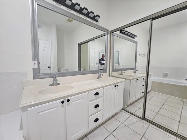 a spacious bathroom with a double vanity sink mirror and bathtub