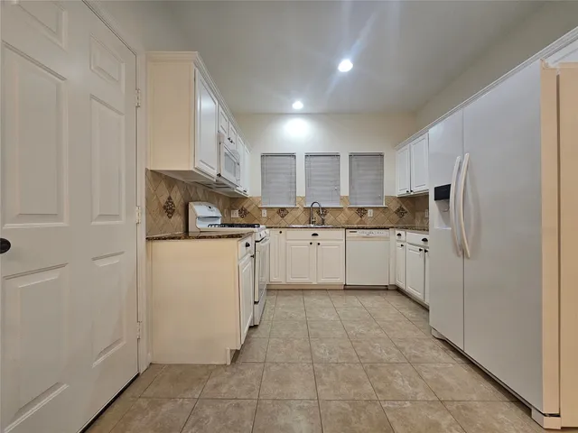 a kitchen with refrigerator cabinets and utility