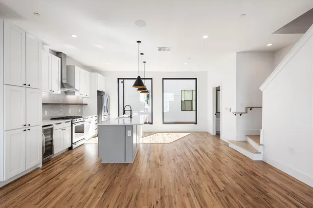 a large kitchen with a wooden floor and stainless steel appliances