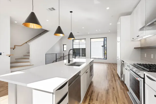 a kitchen with stainless steel appliances granite countertop a sink a stove and a wooden floors