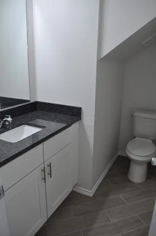 a bathroom with a granite countertop toilet and a sink