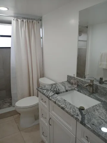 a bathroom with a granite countertop sink toilet and a mirror