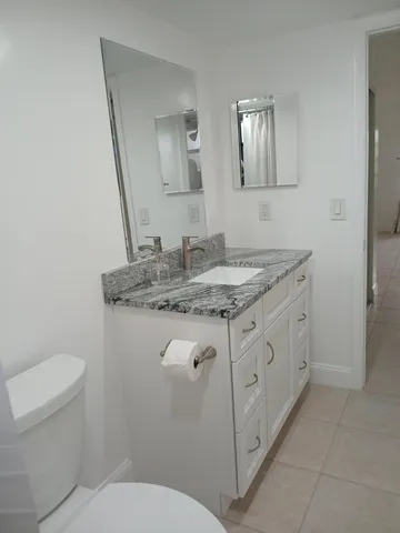 a bathroom with a granite countertop toilet sink and mirror