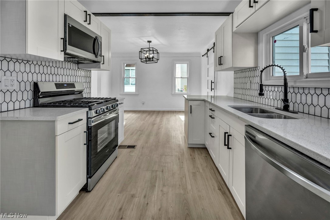 932 Englewood Road Cleveland Heights, OH 44121 - Photo 12 of 32 Kitchen featuring pendant lighting, stainless steel appliances, white cabinets, light hardwood / wood-style flooring, and sink