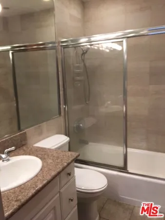 a bathroom with a granite countertop sink toilet and shower