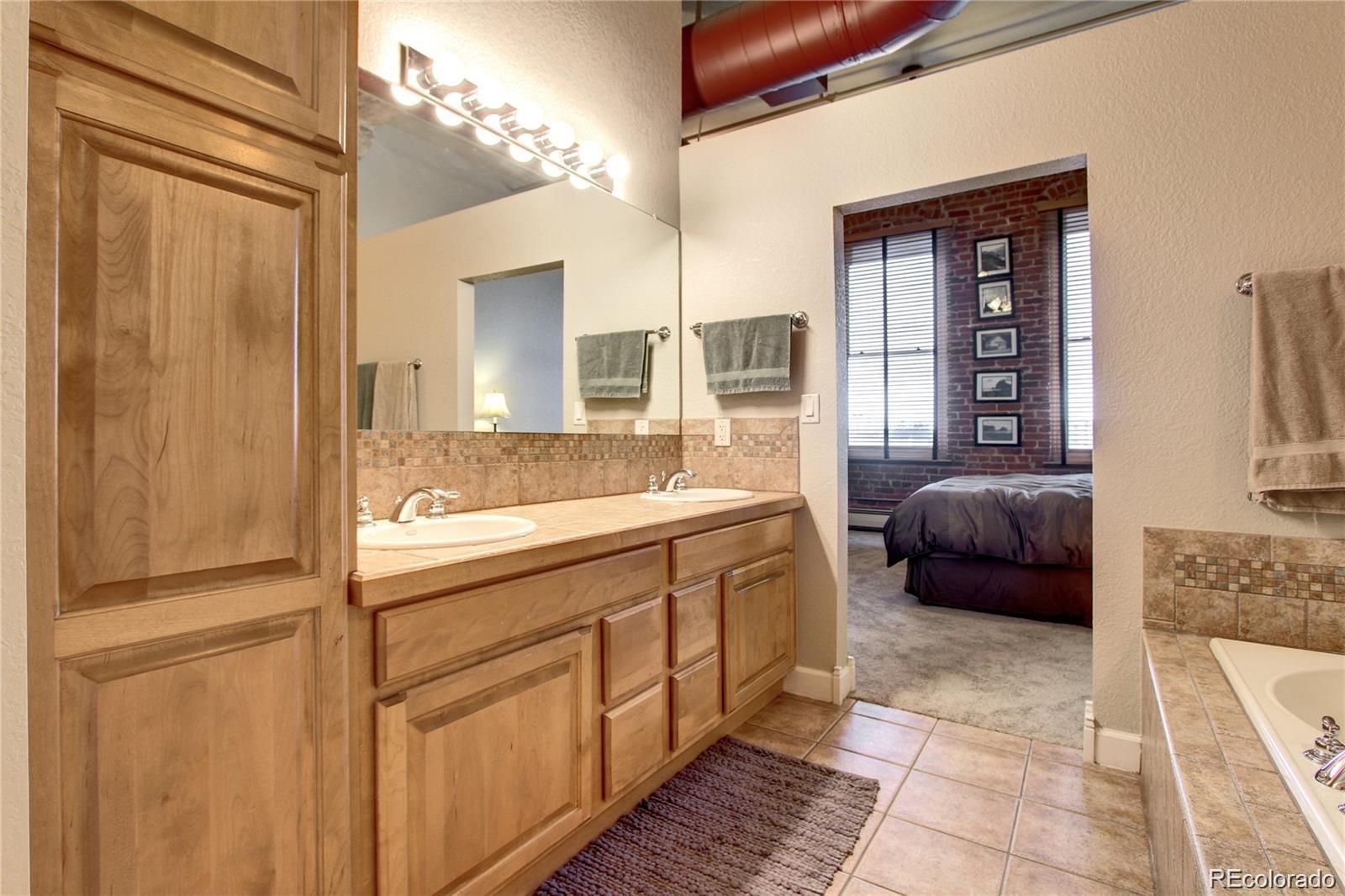 2560 Blake Street, Unit 203 Denver, CO 80205 - Photo 20 of 23 a spacious en suite bathroom with a sink a mirror and a bath tub