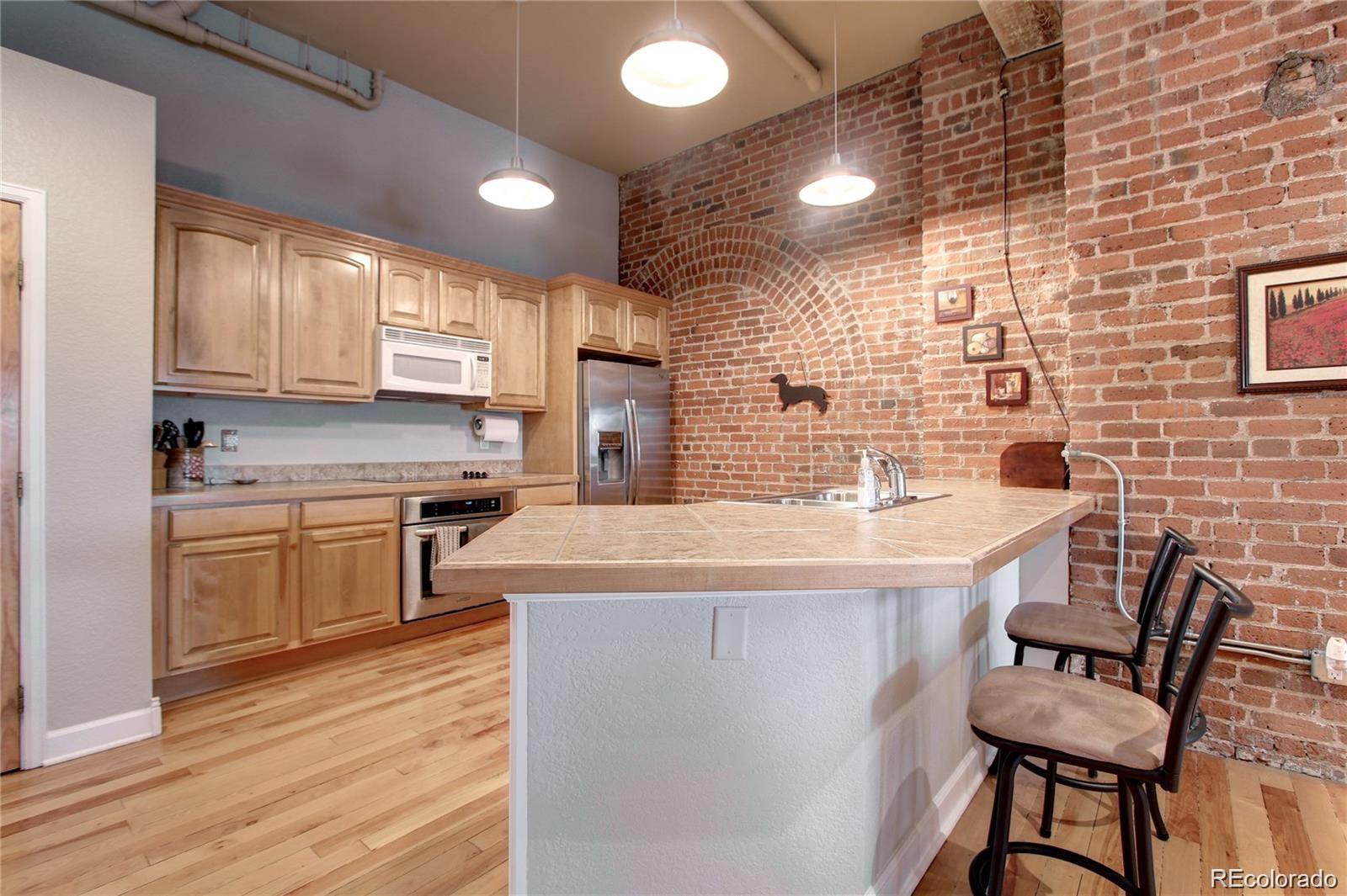 2560 Blake Street, Unit 203 Denver, CO 80205 - Photo 8 of 23 a kitchen with stainless steel appliances kitchen island granite countertop a sink and cabinets
