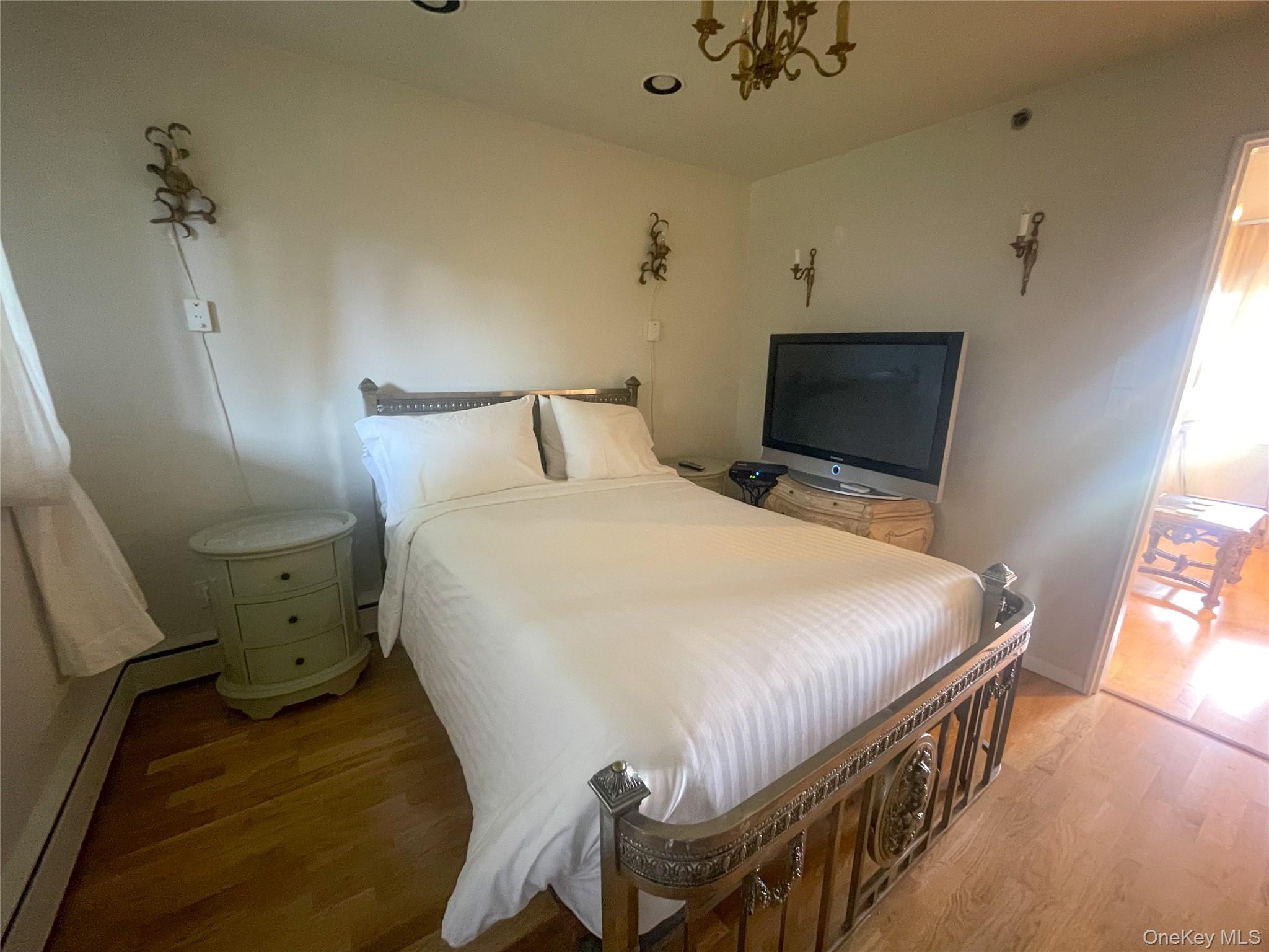 379 Bluff Road, Unit 115 Amagansett, NY 11930 - Photo 17 of 28 a bed sitting in a bedroom next to a window with a flat tv screen on dresser