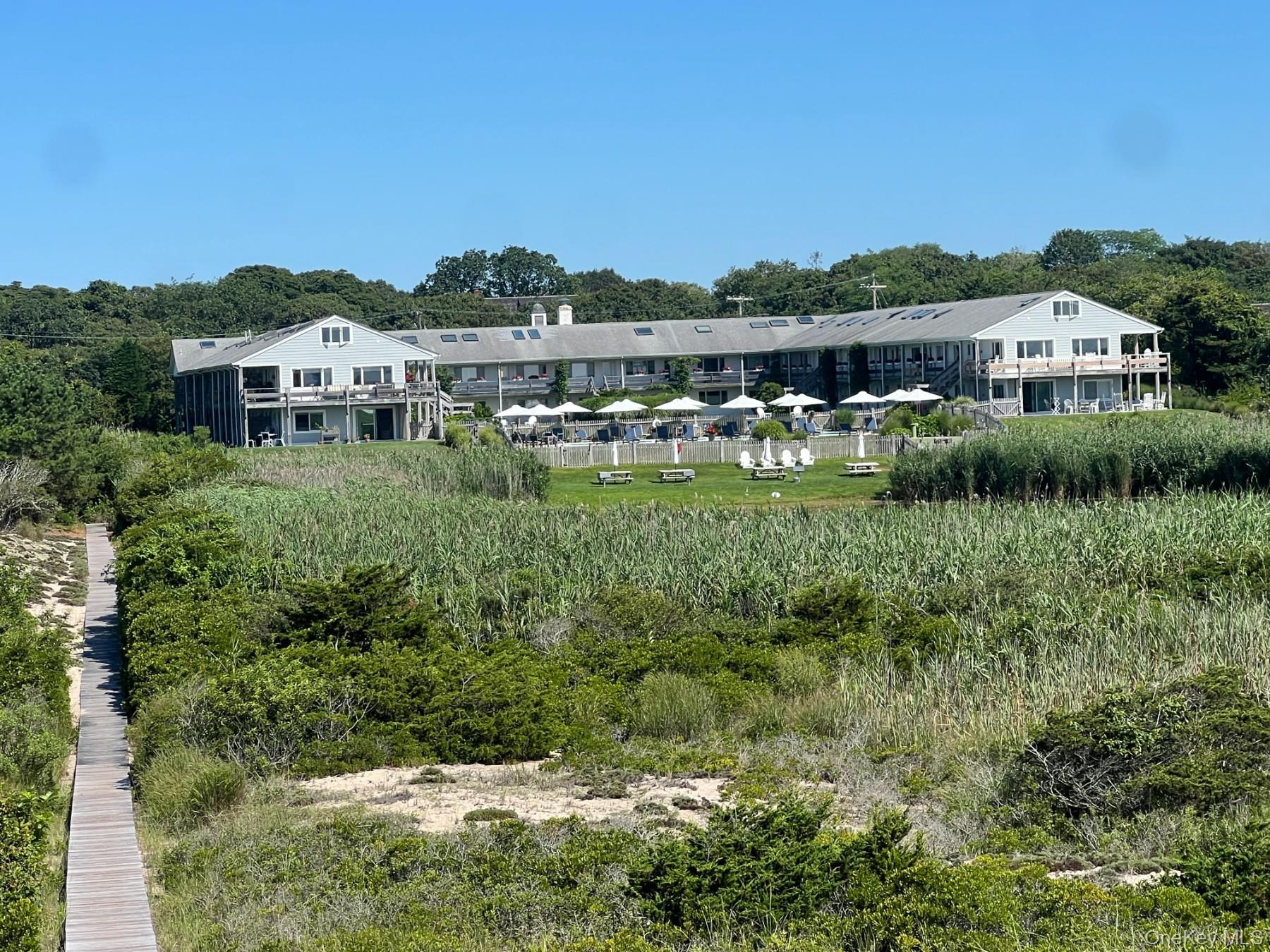 379 Bluff Road, Unit 115 Amagansett, NY 11930 - Photo 28 of 28 a front view of a house with a yard and lake view