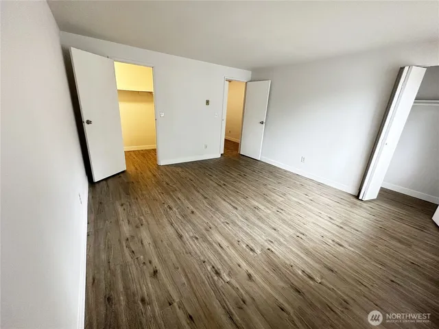 an empty room with wooden floor and mirror