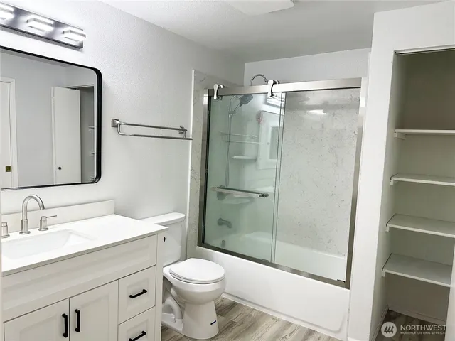 a bathroom with a shower sink vanity mirror and toilet
