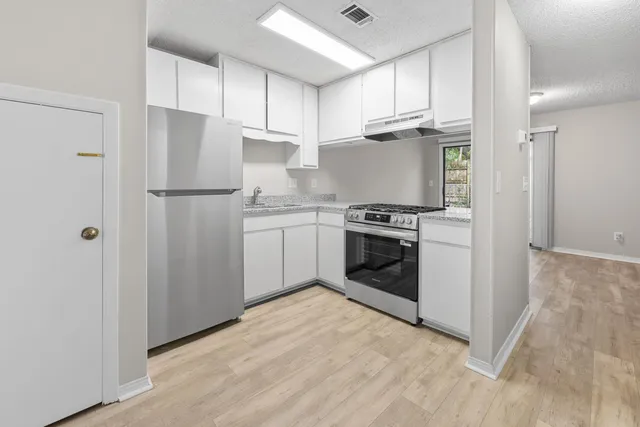 a kitchen with cabinets stainless steel appliances and wooden floor