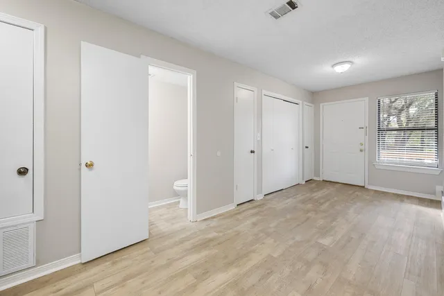 a view of empty room with wooden floor and fan