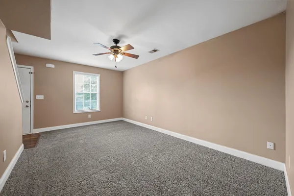 an empty room with windows and chandelier fan