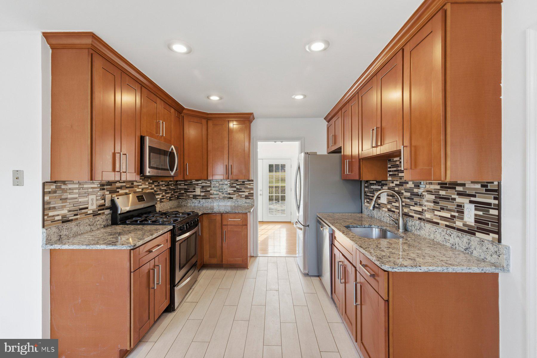 11733 Becket Street Potomac, MD 20854 - Photo 4 of 27 a kitchen with stainless steel appliances granite countertop wooden cabinets and a stove top oven