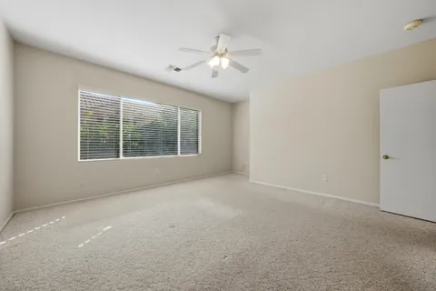 an empty room with windows and chandelier fan