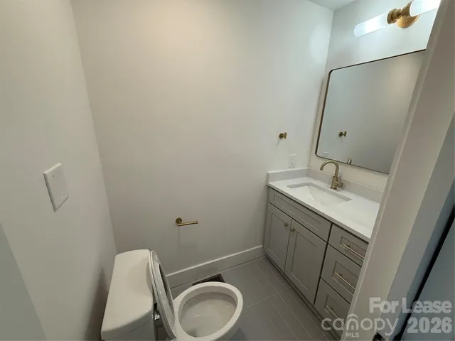 a bathroom with a granite countertop sink and a toilet