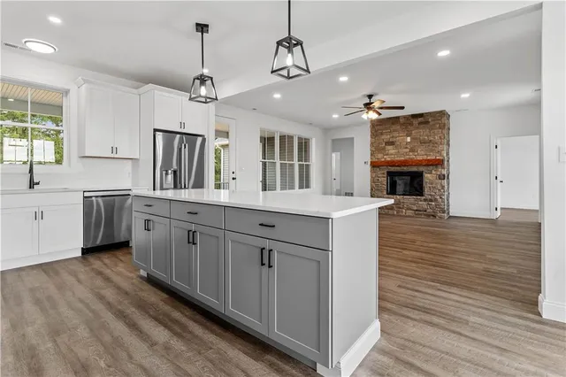 a large kitchen with a center island wooden floor and stainless steel appliances