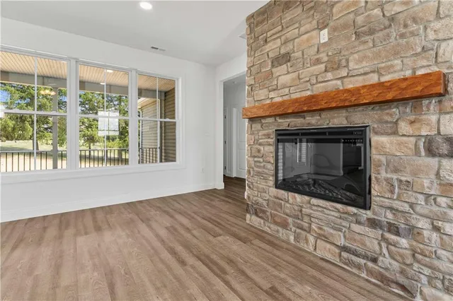a view of an empty room with wooden floor and a fireplace