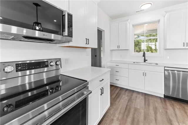 a kitchen with stainless steel appliances a stove a sink and white cabinets