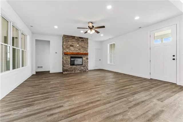 an empty room with wooden floor ceiling fan and windows