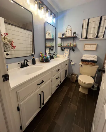a bathroom with double vanity sink a mirror and a toilet