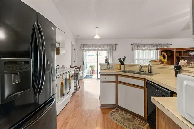 a kitchen with stainless steel appliances granite countertop a refrigerator a sink dishwasher a stove and white countertops with wooden floor