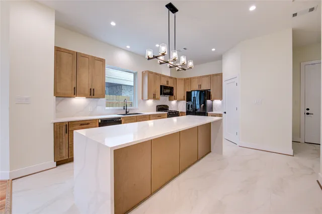 a kitchen with stainless steel appliances granite countertop a sink a stove a refrigerator and cabinets