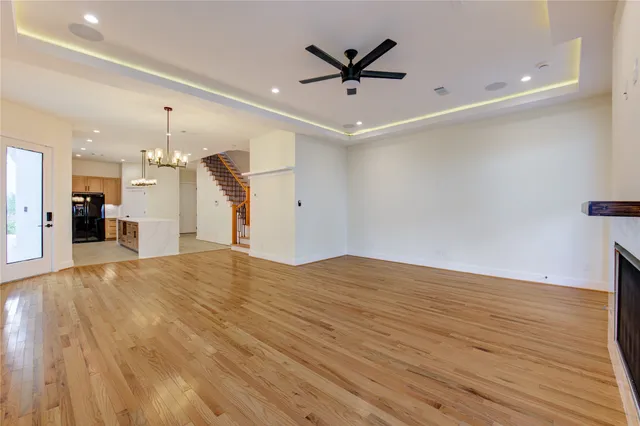 an empty room with wooden floor and ceiling fan
