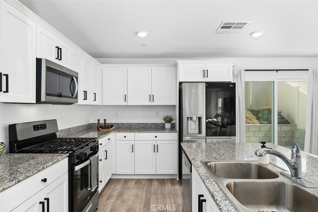 28876 Camaro Drive Winchester, CA 92596 - Photo 11 of 44 a kitchen with stainless steel appliances granite countertop a sink stove and refrigerator