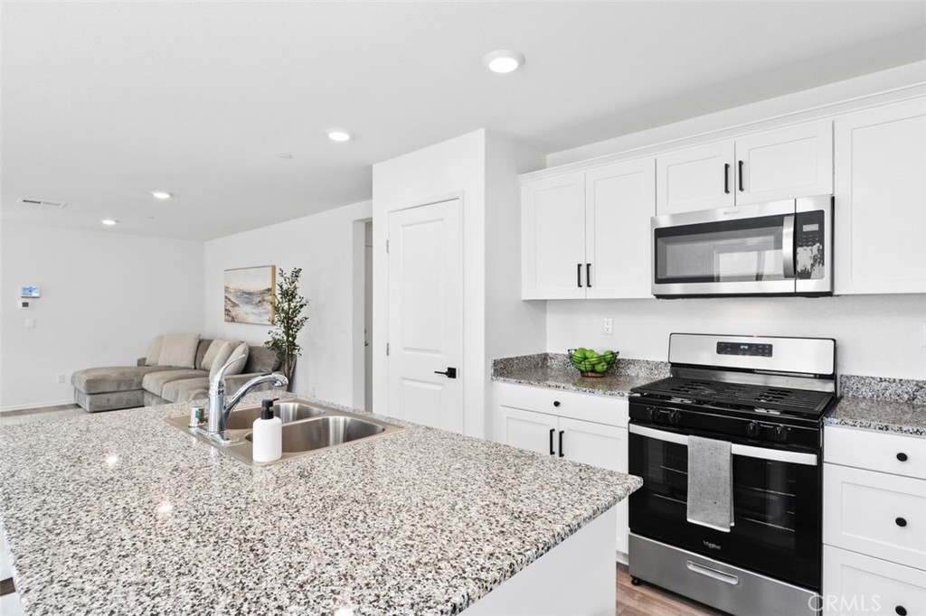 28876 Camaro Drive Winchester, CA 92596 - Photo 13 of 44 a kitchen with stainless steel appliances kitchen island granite countertop a sink stove and cabinets