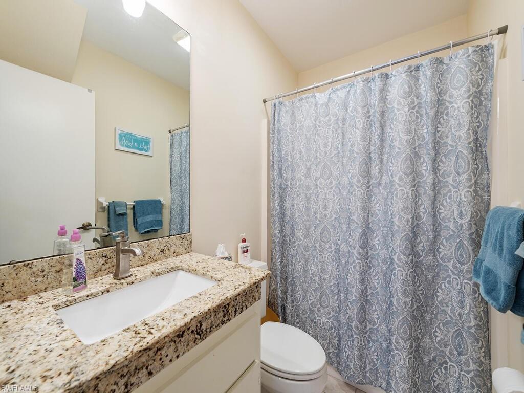508 Bristle Cone Lane, Unit 55 Naples, FL 34113 - Photo 10 of 19 a bathroom with a granite countertop sink and a mirror