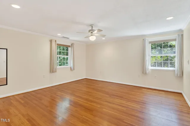 a spacious bedroom with a bed and wooden floor