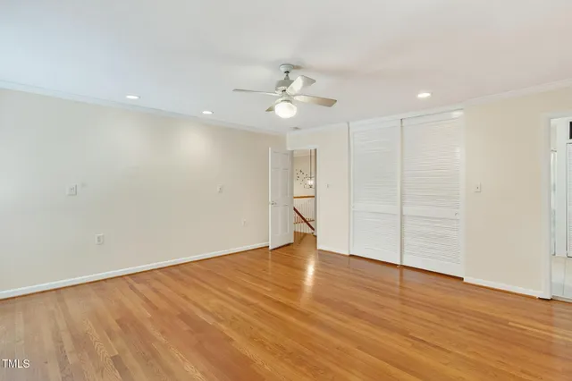 an empty room with wooden floor ceiling fan and windows