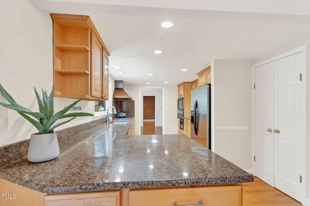 a kitchen with stainless steel appliances granite countertop a refrigerator a sink a stove and cabinets