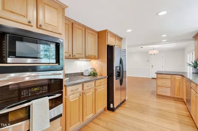 a kitchen with stainless steel appliances granite countertop a sink and wooden floors