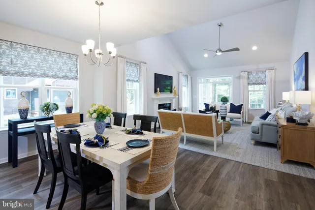 a view of a dining room and livingroom with furniture wooden floor a chandelier and a rug