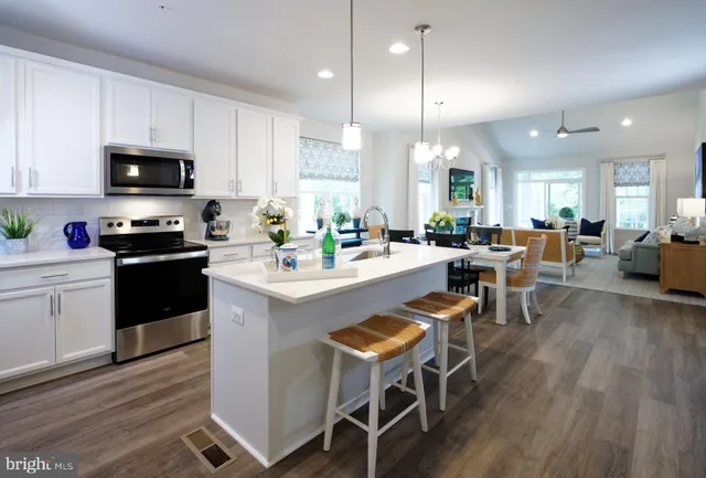 a kitchen with stainless steel appliances a dining table chairs stove microwave and cabinets