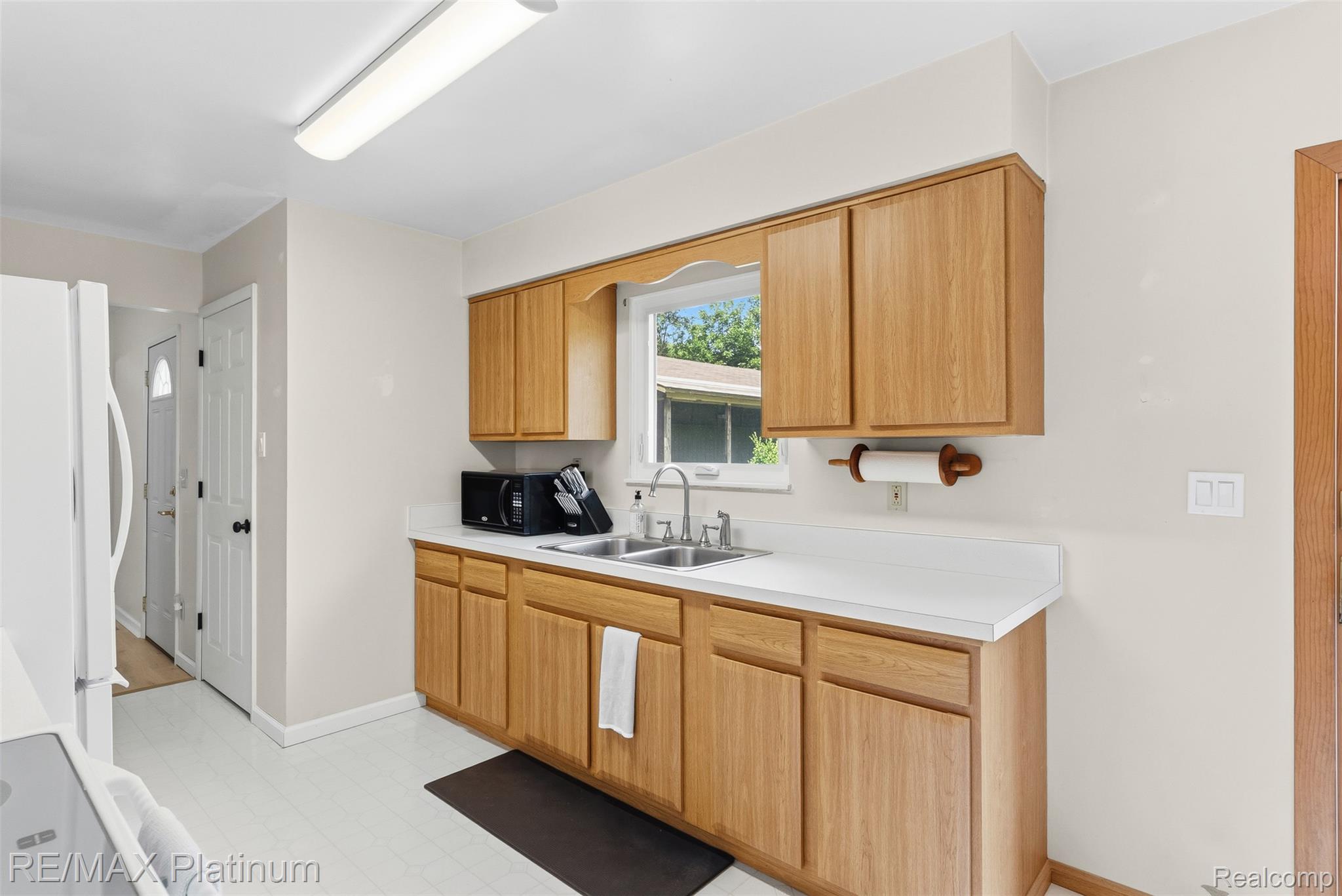 8370 West Rolston Road Linden, MI 48451 - Photo 12 of 36 Kitchen area featuring light wood-finish cabinetry, a double basin stainless steel sink with a window overhead, and light-toned countertops