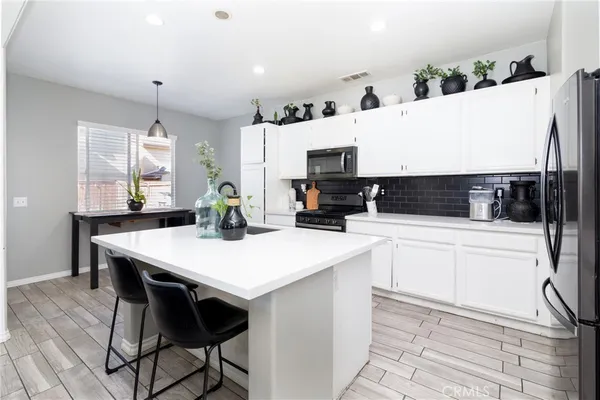 a kitchen with stainless steel appliances kitchen island granite countertop a table chairs sink and cabinets