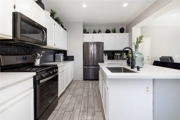 a kitchen with refrigerator a microwave a sink and cabinets