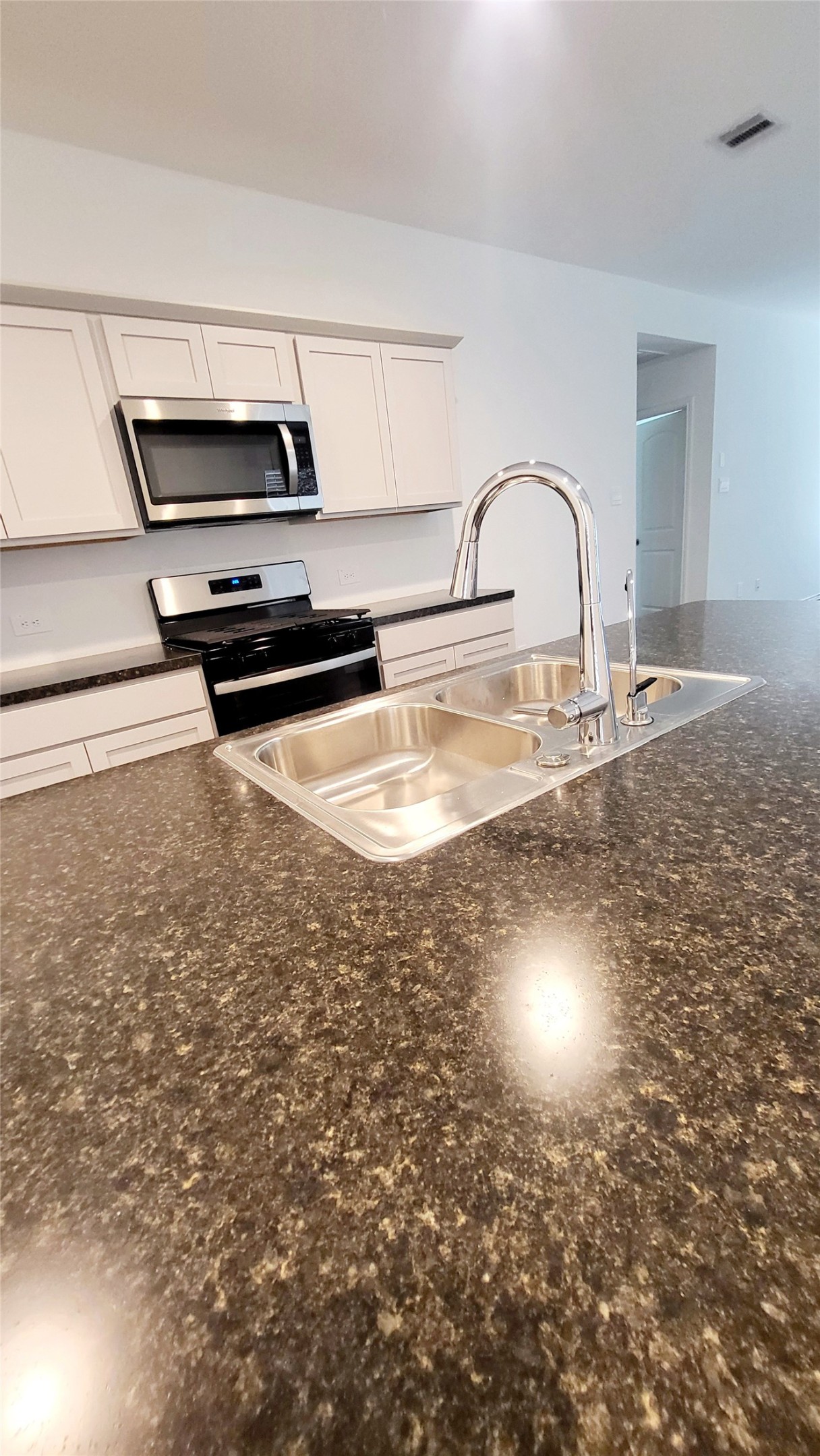 23835 Sunland Park Spring, TX 77373 - Photo 4 of 14 The kitchen features modern appliances, white cabinetry, and granite countertops, with a double-basin sink and a high-arc faucet.