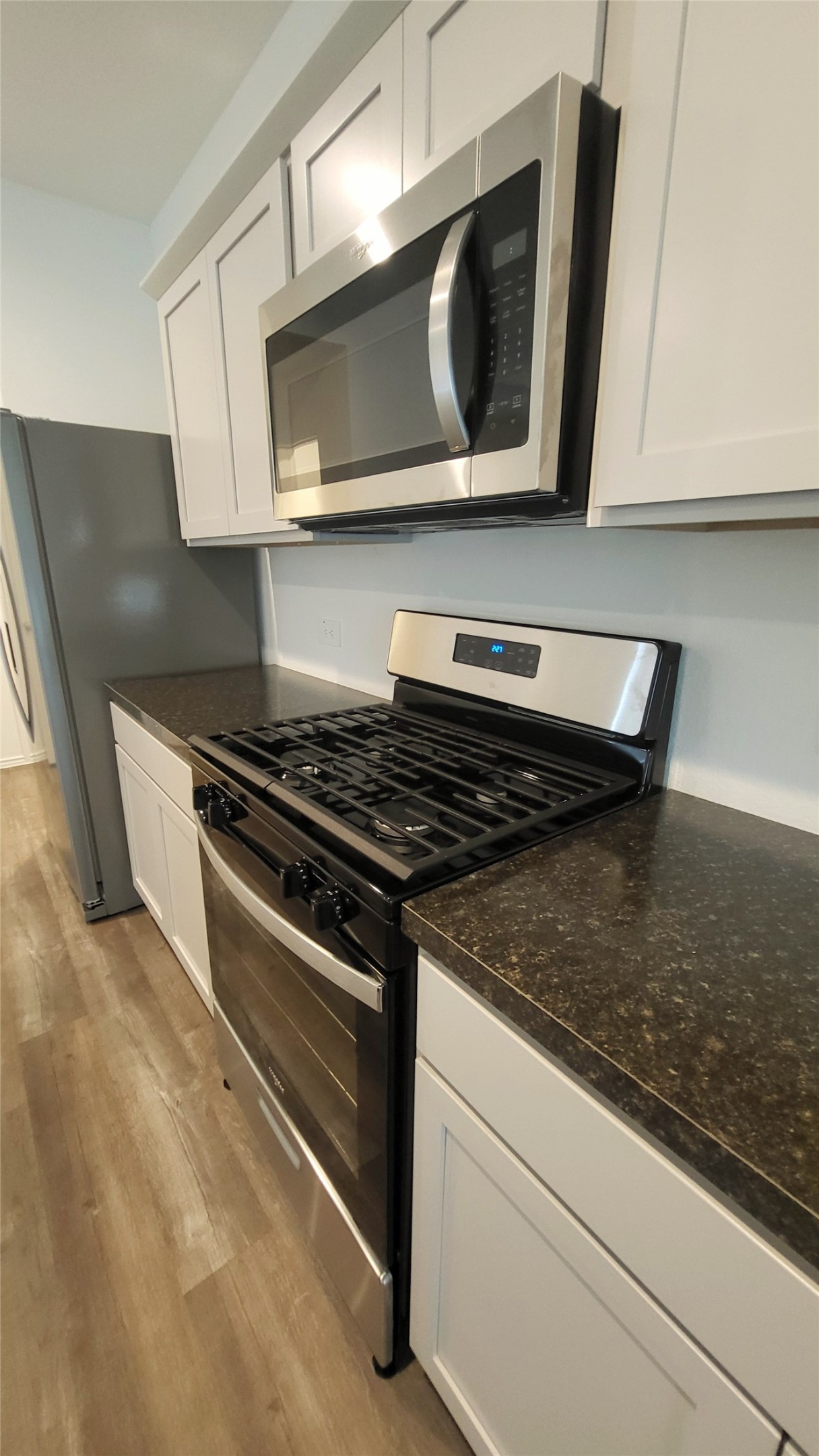 23835 Sunland Park Spring, TX 77373 - Photo 5 of 14 This kitchen features modern stainless steel appliances, including a gas stove and a built-in microwave, set against white cabinetry and dark countertops, with a sleek, contemporary design.