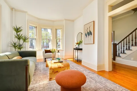 a living room with furniture floor to ceiling window and a flat screen tv