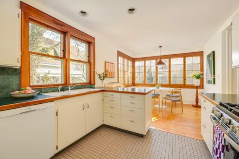 a large white kitchen with granite countertop a large window and a sink